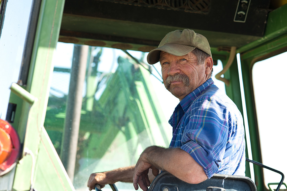 a farmer sits on his tractor, smiling